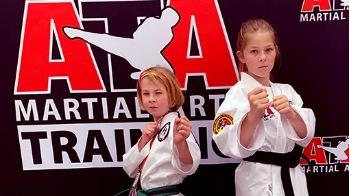 Two young Tiger students in front of the ATA banner